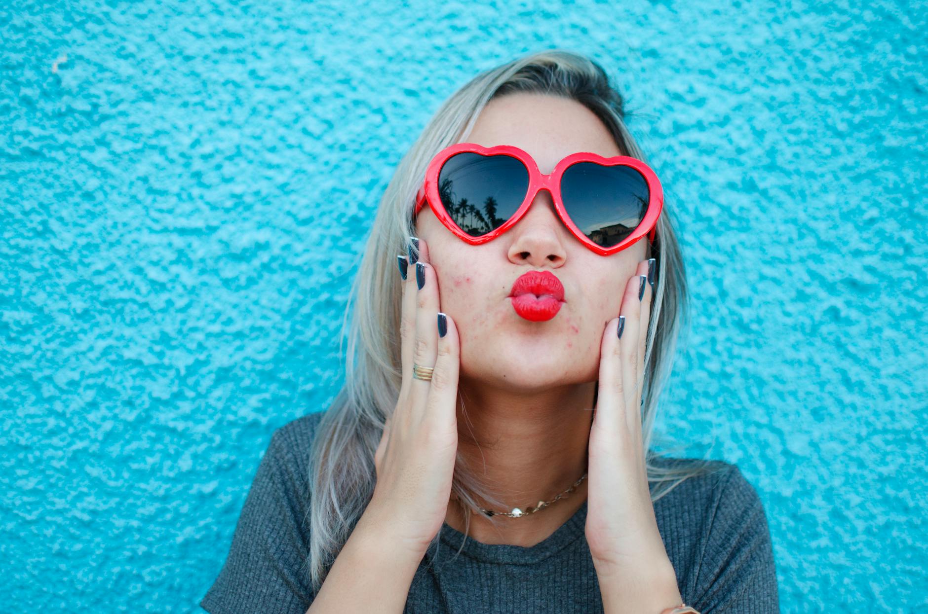 blonde woman in sunglasses blowing kisses
